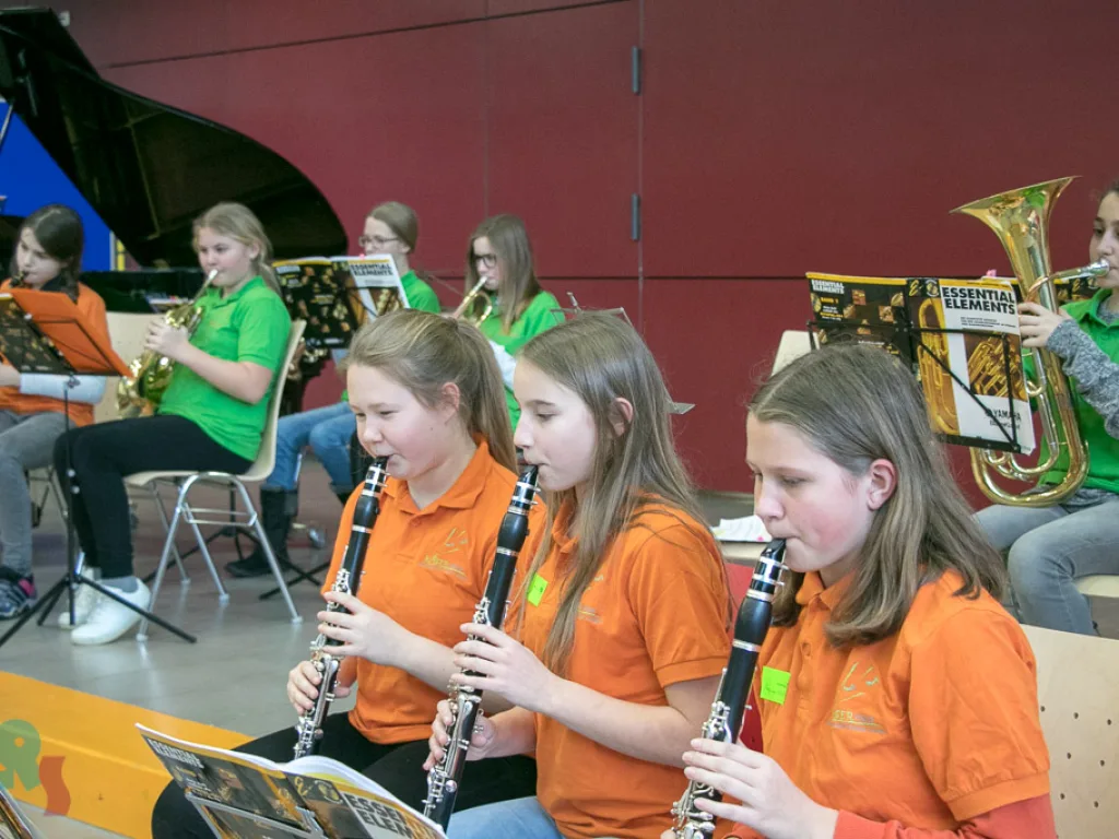 Drei Jugendliche spielen Klarinette im Orchester.